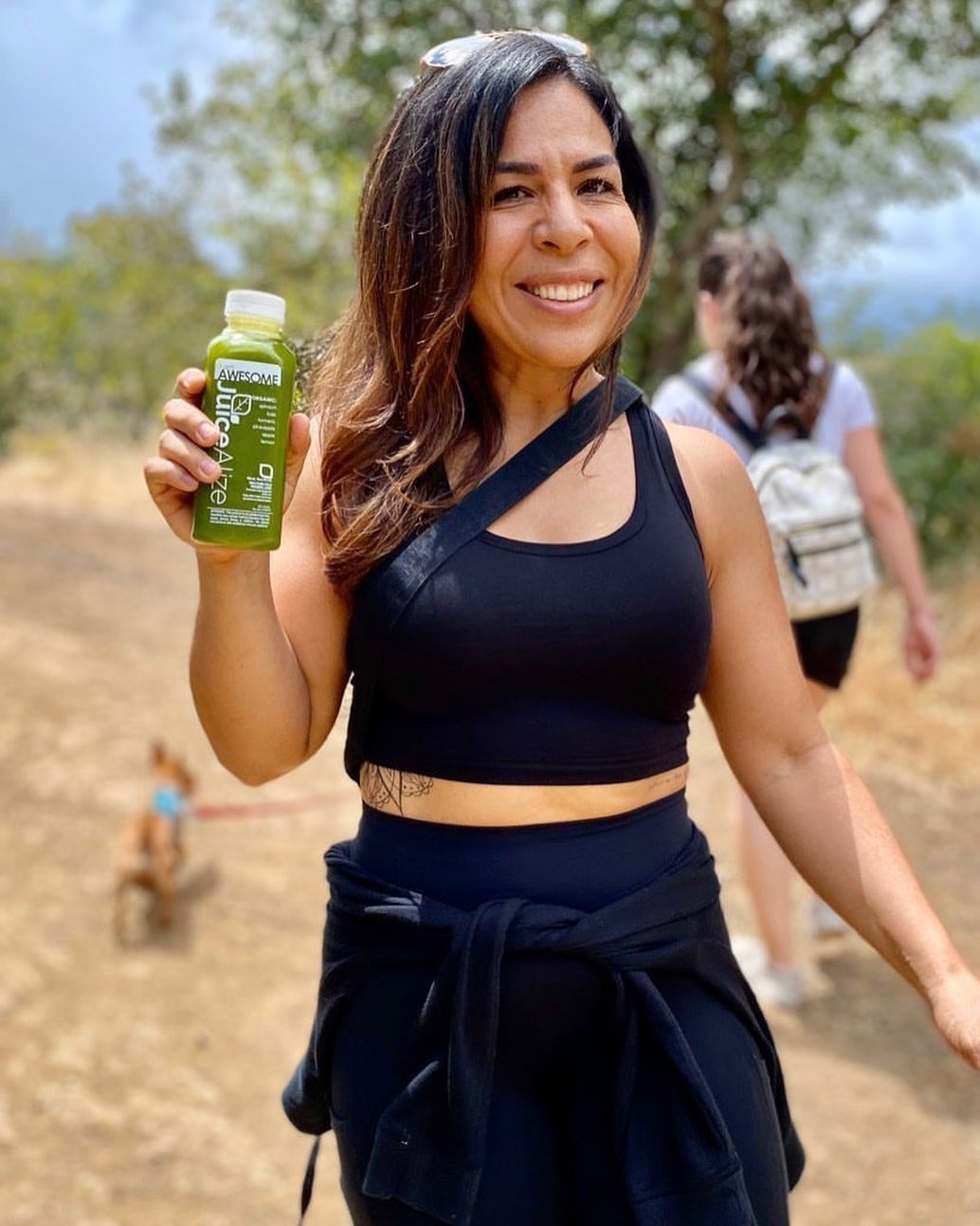 Hiker holding an i am AWESOME green juice on the trail
