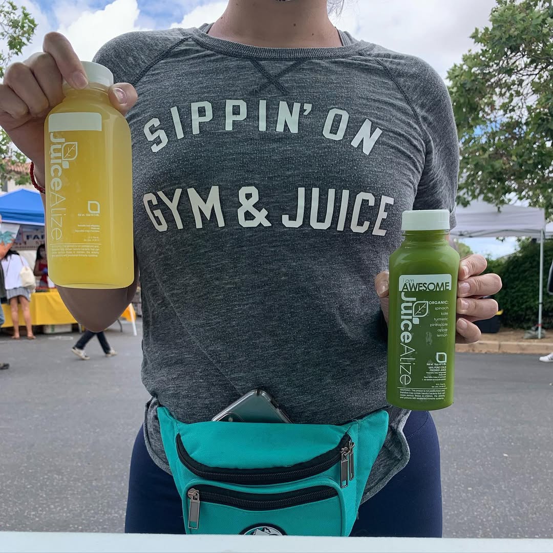 Two JuiceAlize bottles at a market in a Gym & Juice tee
