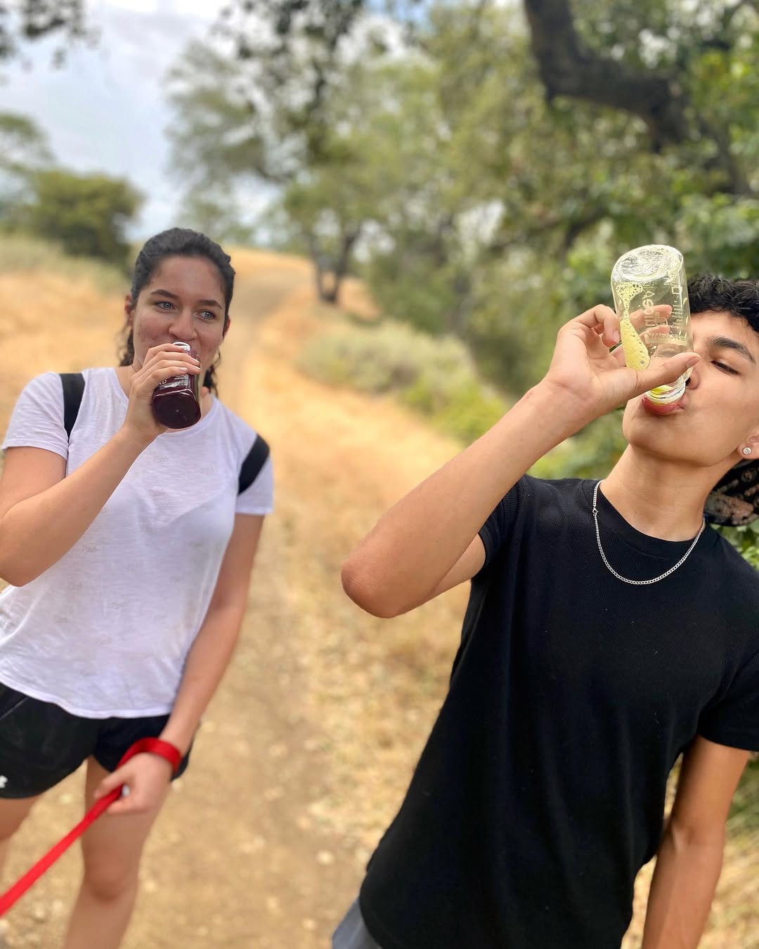 Two hikers drinking cold-pressed juice on a trail