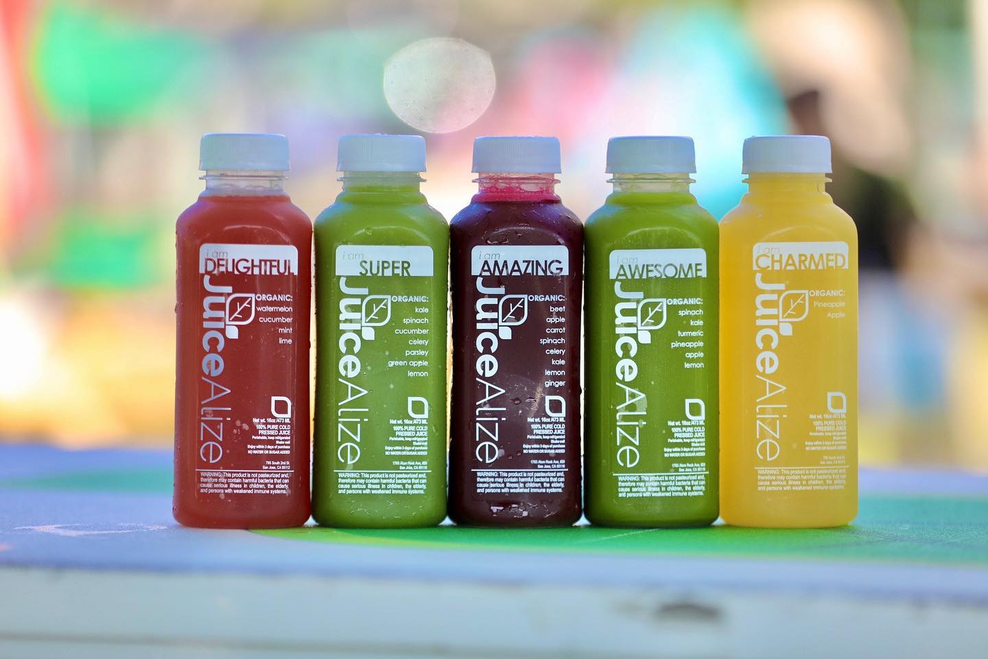 Five JuiceAlize cold-pressed juice bottles — I Am Delightful, Super, Amazing, Awesome, and Charmed